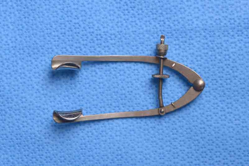This is a rigid speculum which allows for adjusting of the width of the palpebral fissure. In addition, it has guards to keep the eyelashes away during surgery although this can also be accomplished with the use of surgical drapes. A possible disadvantage of this speculum is that it can create significant force on the eyelids which may increase the rate of post-operative ptosis or other eyelid malpositions.